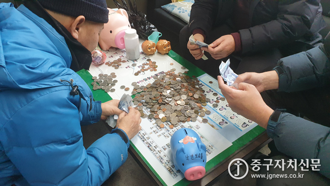 환경미화원 들이 돼지저금통을 열고 동전을 세고 있다.