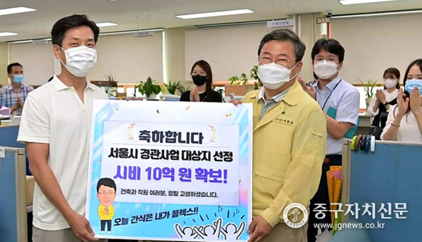 서양호 구청장이 건축과를 찾아 시비확보 판넬을 들어보이고 있다.