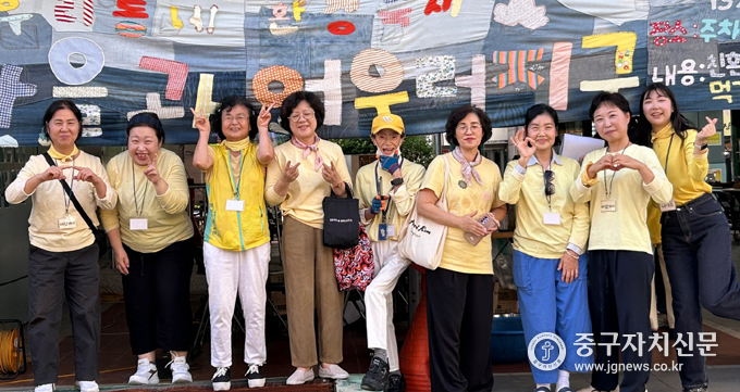 신당종합사회복지관 환경캠페이너 '바람개비'와 헌 옷을 바느질해서 직접 만든 새활용 현수막 앞에서 기념촬영을 하고 있다.