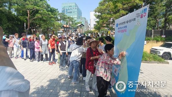 한국자총 중구지회장이 신당마을마당에서 열린 6.25전쟁 제75주년 사진전 및 전쟁음식 체험에서 참석자들이 태극기 통일지도를 그리고 있다.<br>
