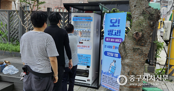  공원등에 설치된 오! 빙고! 양심 생수냉장고에서 생수버튼을 누르고 있다.
