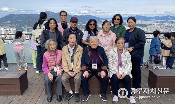 장기요양 어르신 및 보호자가 함께하는 남산 나들이 행사에서 참여자들이 서울시내를 배경으로 기념촬영을 하고 있다.